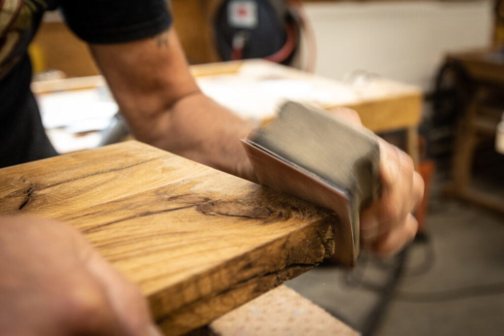 Ein Mitarbeiter schleift die Kanten eines Eichenbretts